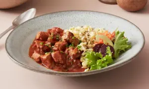 Herzhaftes ungarisches Gulasch mit Nockerln als Beilage, garniert mit frischem Salat und Rote Bete.