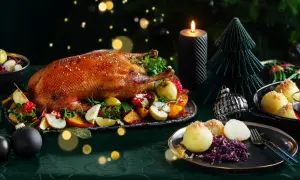 Festliches weihnachtsessen einen tag vorher vorbereiten: goldbraune Gans mit Früchten, Klößen und Rotkohl, Kerzenlicht und Weihnachtsdeko.