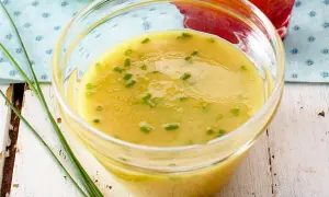 Ein Glas mit cremigem honig senf dressing, garniert mit Schnittlauch. Perfekt für Salate!