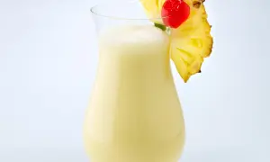 Cremiger Pina Colada mit Ananasstück und Kirsche garniert.