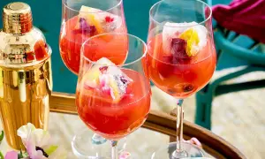 Erfrischendes Aperol Spritz Rezept: Drei Gläser mit leuchtend rotem Aperol, Eiswürfeln und Fruchtgarnitur. Ein goldener Shaker steht bereit.