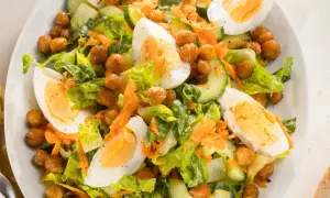 Ein bunter gemischter Salat mit knackigem Salat, Gurkenscheiben, geraspelten Karotten, Kichererbsen und gekochten Eiern.