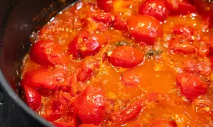 Frische, glänzende Tomaten köcheln in einer Pfanne zu einer aromatischen Tomatensauce.