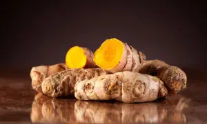Ein Haufen ganzer und halber Kurkumawurzeln. Man sieht, wie sieht kurkuma aus: außen braun und innen leuchtend orange.