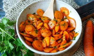 Schmackhafte Karotten-Rezepte: Glasierte Karotten mit Petersilie in einer Schüssel, daneben frische Karotten.