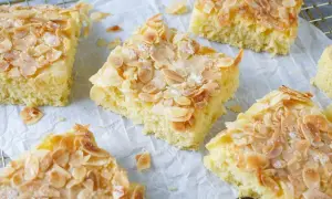 Omas saftiger Buttermilchkuchen, goldbraun gebacken und mit knusprigen Mandelblättchen bestreut, wartet darauf, genossen zu werden.
