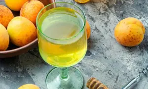 Frische Aprikosen und ein Glas goldener Likör – die Zutaten, um Mirabellenschnaps selber zu machen.