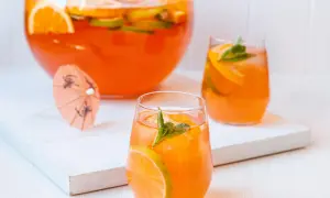 Erfrischende Aperol Bowle mit Orangen- und Limettenscheiben, garniert mit Minze. Perfekt für heiße Sommertage.