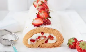 Biskuitrolle Grundrezept mit 5 Eiern, gefüllt mit Sahne und Erdbeeren, bestäubt mit Puderzucker.