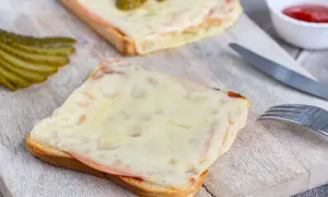 Zwei überbackene Scheiben Brot mit Schinken und Käse, garniert mit Gewürzgurken. Eine Karlsbader Schnitte, perfekt für einen herzhaften Snack.