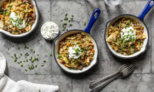 Herzhafte spitzkohl rezepte mit hackfleisch, garniert mit einem Klecks Sauerrahm und Schnittlauch, serviert in kleinen Pfannen.