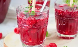 Erfrischende alkoholfreie Bowle mit Himbeeren und Minze in dekorativen Gläsern.