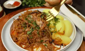 Zwiebelfleisch nach Omas Art: Zartes Fleisch mit karamellisierten Zwiebeln und Salzkartoffeln, garniert mit Petersilie. Ein Klassiker, der immer schmeckt.