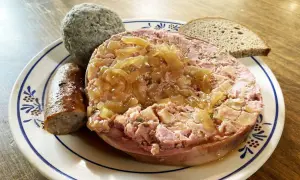 Saumagen-Rezept: Ein deftiger Saumagen mit Zwiebeln, Bratwurst und Brot auf einem Teller.