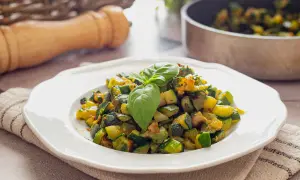Herzhafte zucchini pfanne, frisch zubereitet und mit Basilikum garniert, serviert auf einem weißen Teller.
