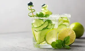Zwei erfrischende Aperitifs mit Gurke, Limette und Minze, garniert mit Blaubeeren.