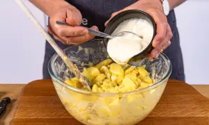 Hände geben Mayonnaise zu Kartoffeln für norddeutschen Kartoffelsalat.