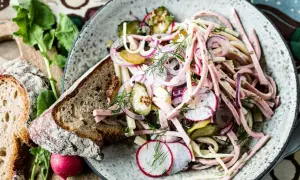 Ein bayerischer Wurstsalat, garniert mit Radieschen, Zwiebeln und Dill, serviert mit Bauernbrot.