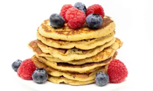 Stapel zuckerfreier Bananen-Pancakes, garniert mit frischen Himbeeren und Blaubeeren. Ein gesunder Genuss!