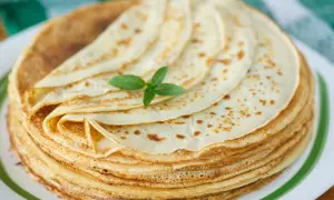 Ein Stapel goldbrauner Pfannkuchen, garniert mit Minze. Ein köstliches Pfannkuchen-Rezept, das zum Genießen einlädt.