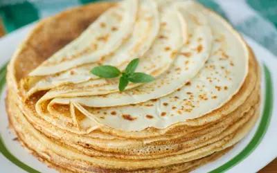 Ein Stapel goldbrauner Pfannkuchen, garniert mit Minze. Ein köstliches Pfannkuchen-Rezept, das zum Genießen einlädt.