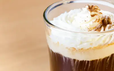 Ein erfrischender Eiskaffee mit Sahne und Zimt bestreut, perfekt für einen warmen Tag.