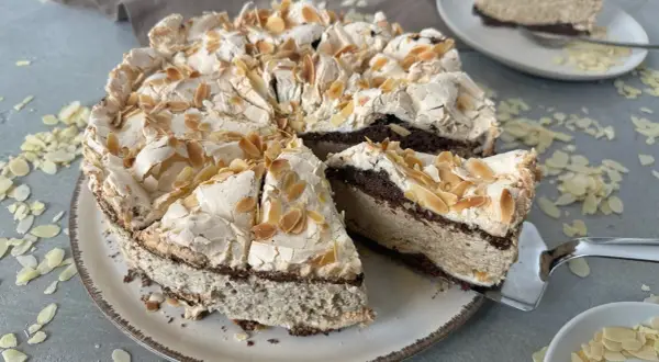Eine himmelstorte mit kirschen, verziert mit Mandelblättchen, wartet darauf, angeschnitten zu werden.