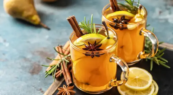 Zwei Gläser mit einem warmen Hot Toddy Rezept, garniert mit Zimt, Sternanis, Zitrone und Birne.