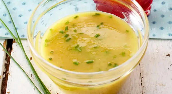 Ein Glas mit cremigem honig senf dressing, garniert mit Schnittlauch. Perfekt für Salate!