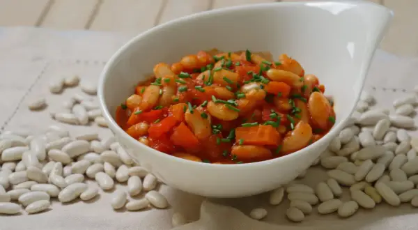 Schmackhafte weiße Bohnen in Tomatensoße, garniert mit Schnittlauch. Die Frage "wie lange bohnen kochen" wird hier visuell beantwortet.