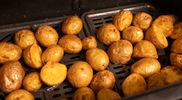 Kleine, goldbraune Kartoffeln, die in einem Airfryer zubereitet werden. Sie sehen aus, als wären sie perfekt zum Servieren, wenn die Drillinge kochen.