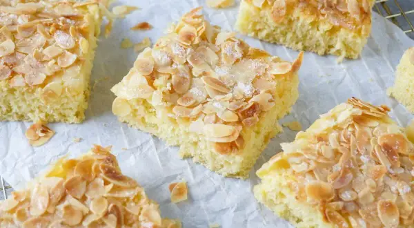 Omas saftiger Buttermilchkuchen, goldbraun gebacken und mit knusprigen Mandelblättchen bestreut, wartet darauf, genossen zu werden.