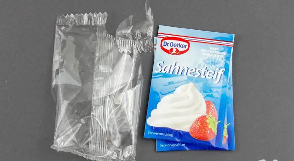 Ein Päckchen Dr. Oetker Sahnesteif, ideal zum Sahne steif schlagen, liegt neben einer leeren, aufgerissenen Plastiktüte.