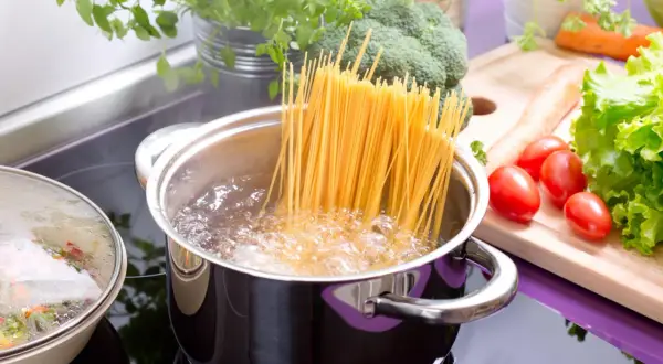 Spaghetti kochen in sprudelndem Wasser. Frisches Gemüse wie Brokkoli, Karotten und Tomaten liegen bereit für eine leckere Mahlzeit.