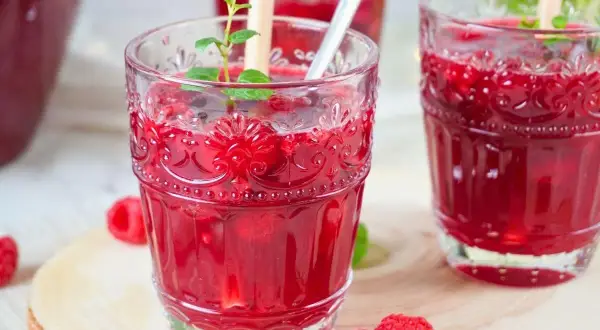 Erfrischende alkoholfreie Bowle mit Himbeeren und Minze in dekorativen Gläsern.