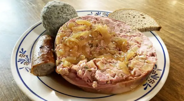 Saumagen-Rezept: Ein deftiger Saumagen mit Zwiebeln, Bratwurst und Brot auf einem Teller.