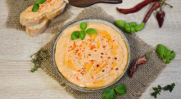 Cremiger Tomate Mozzarella Aufstrich mit Basilikum und Chili, serviert auf Baguette und in einer Schale.