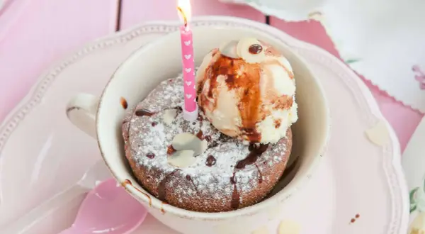 Schokoladenkuchen im Tassenformat mit Eis, Schokosauce, Mandelsplittern und einer Kerze. Perfekt zum Kuchen backen mit Tassenangabe!