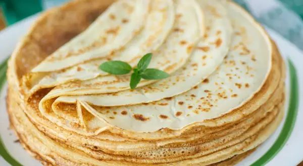 Ein Stapel goldbrauner Pfannkuchen, garniert mit Minze. Ein köstliches Pfannkuchen-Rezept, das zum Genießen einlädt.