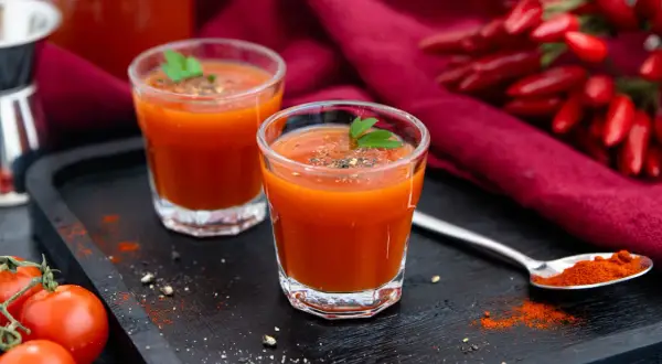Zwei Gläser scharfer Tomatensaft, perfekt für ein mexikaner rezept. Mit frischen Tomaten und Chilis garniert.