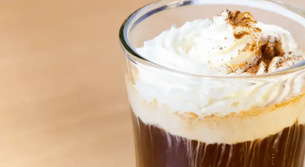 Ein erfrischender Eiskaffee mit Sahne und Zimt bestreut, perfekt für einen warmen Tag.