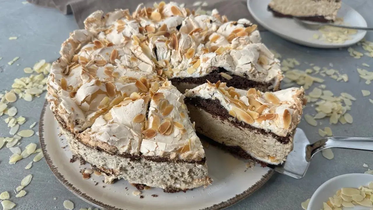 Eine himmelstorte mit kirschen, verziert mit Mandelblättchen, wartet darauf, angeschnitten zu werden.