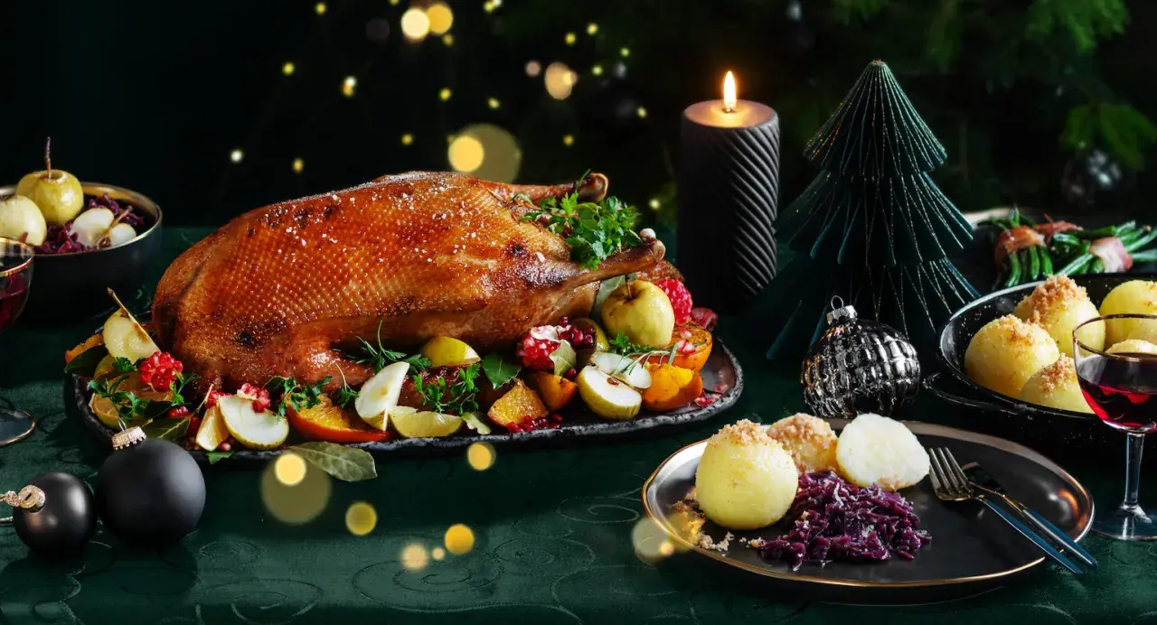 Festliches weihnachtsessen einen tag vorher vorbereiten: goldbraune Gans mit Früchten, Klößen und Rotkohl, Kerzenlicht und Weihnachtsdeko.