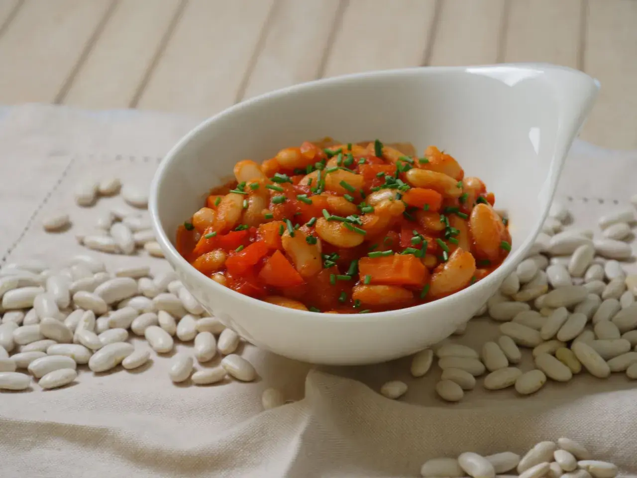 Schmackhafte weiße Bohnen in Tomatensoße, garniert mit Schnittlauch. Die Frage "wie lange bohnen kochen" wird hier visuell beantwortet.