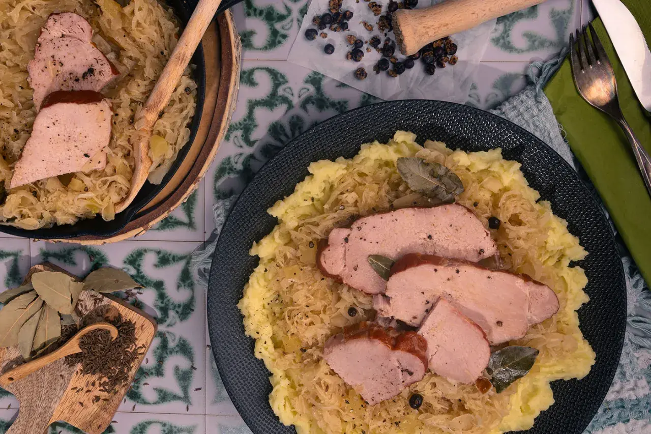 Omas Sauerkraut mit zartem Schweinebraten und Kartoffelpüree. Ein deftiges Gericht, das an Zuhause erinnert.