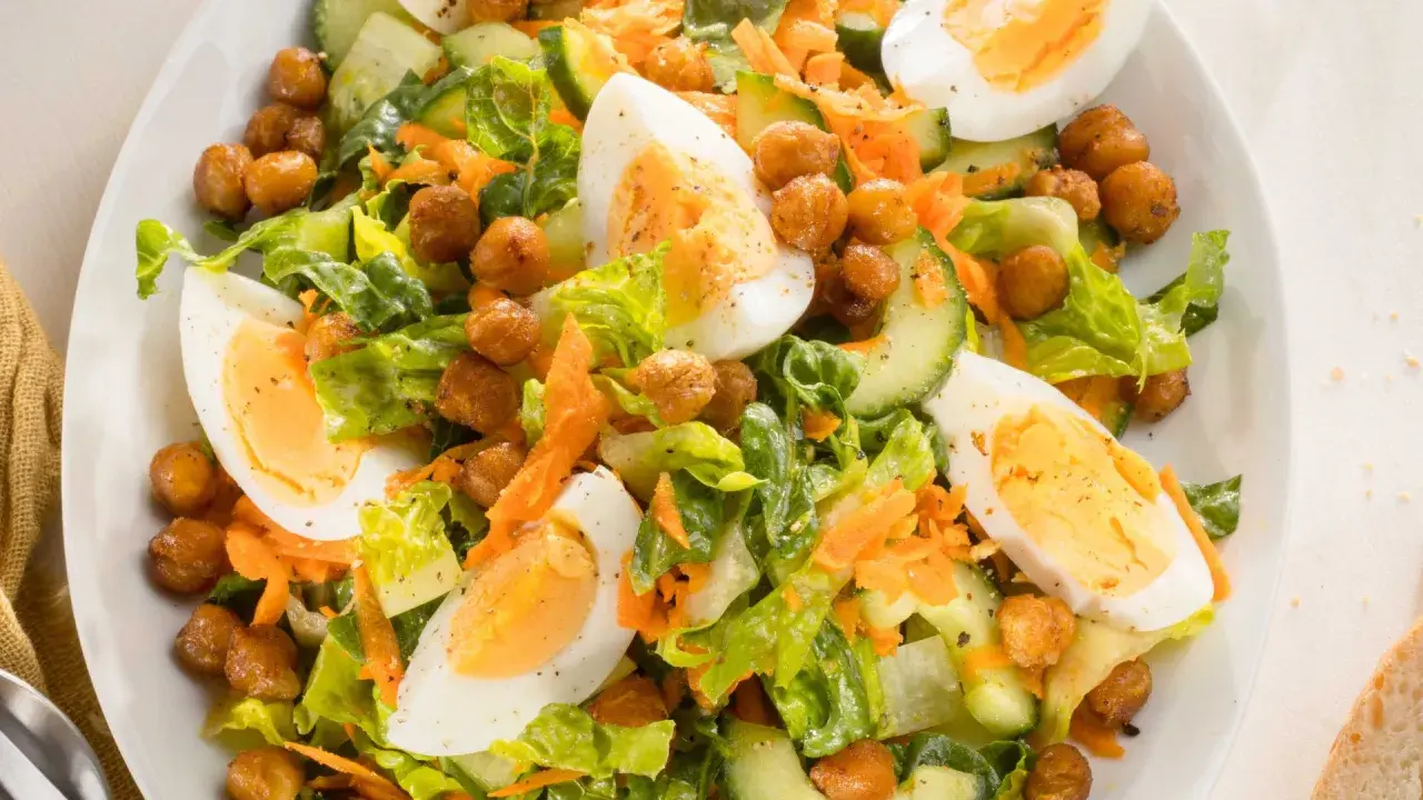 Ein bunter gemischter Salat mit knackigem Salat, Gurkenscheiben, geraspelten Karotten, Kichererbsen und gekochten Eiern.