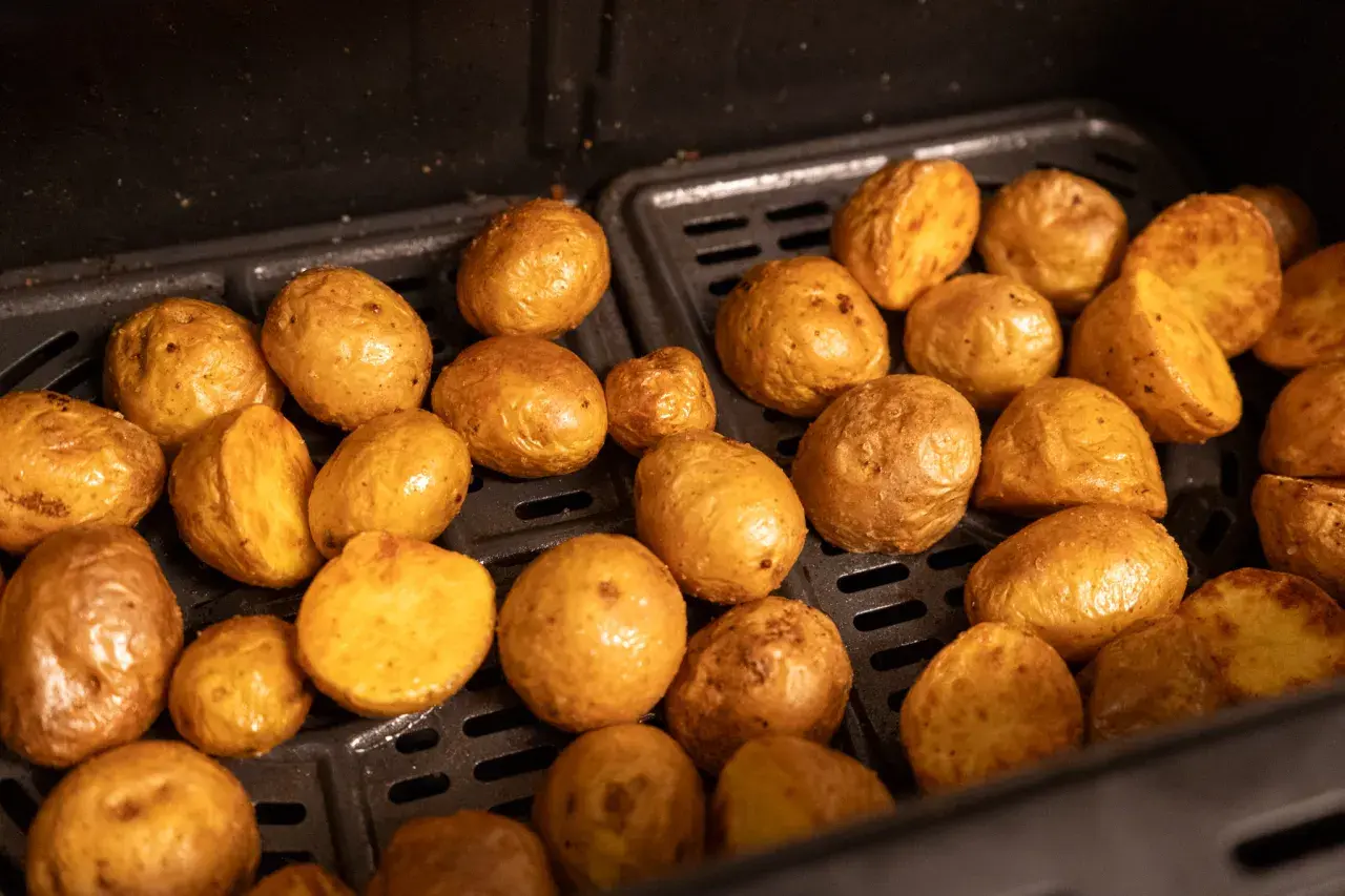 Kleine, goldbraune Kartoffeln, die in einem Airfryer zubereitet werden. Sie sehen aus, als wären sie perfekt zum Servieren, wenn die Drillinge kochen.