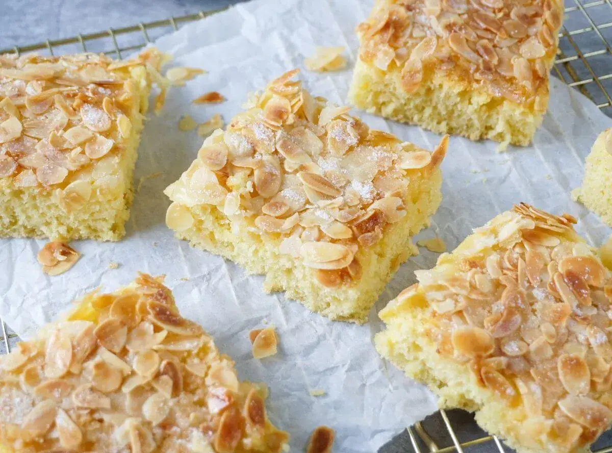 Omas saftiger Buttermilchkuchen, goldbraun gebacken und mit knusprigen Mandelblättchen bestreut, wartet darauf, genossen zu werden.