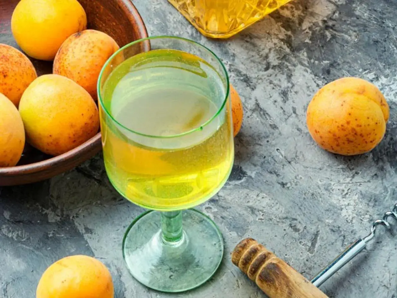 Frische Aprikosen und ein Glas goldener Likör – die Zutaten, um Mirabellenschnaps selber zu machen.
