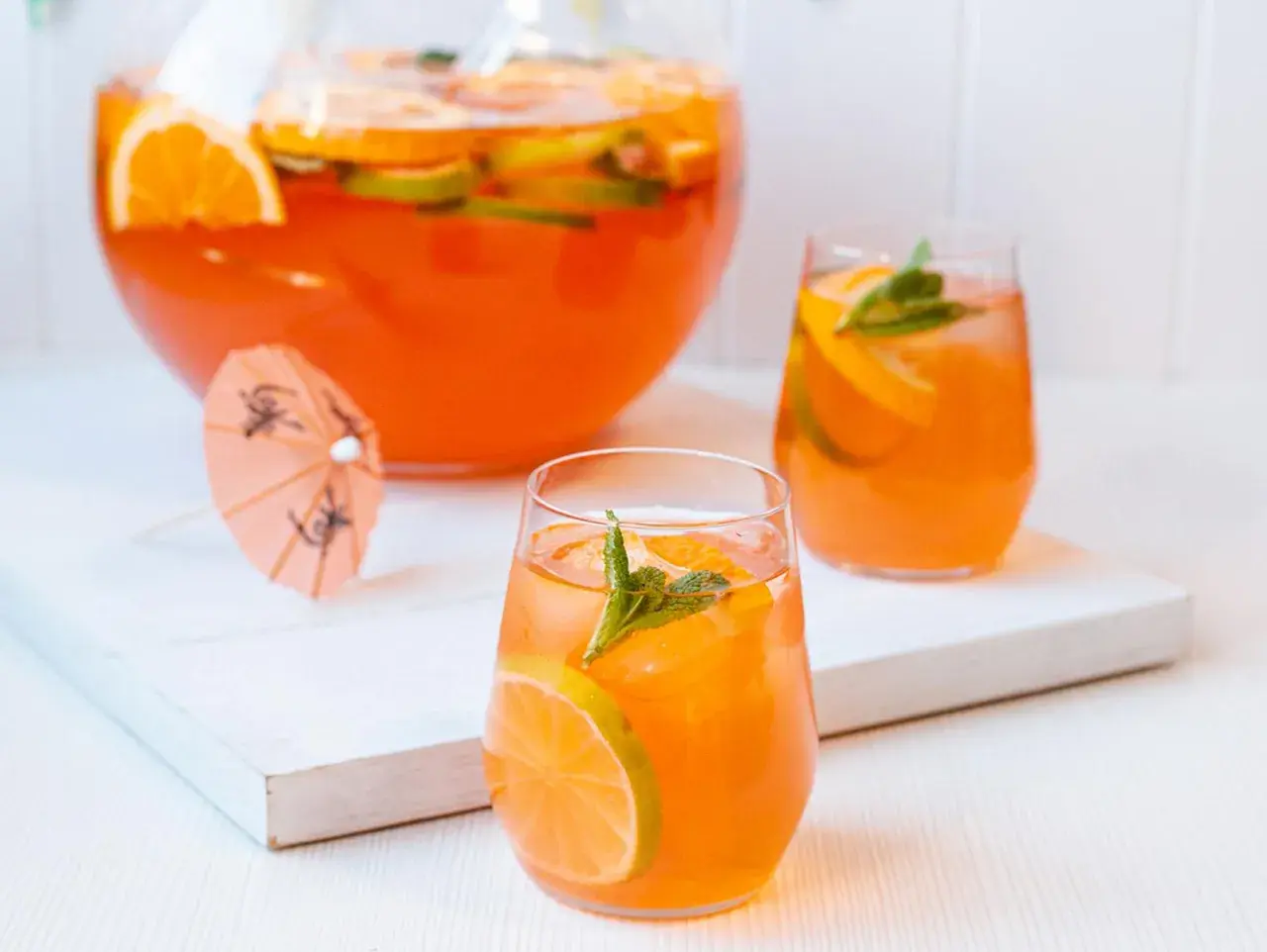 Erfrischende Aperol Bowle mit Orangen- und Limettenscheiben, garniert mit Minze. Perfekt für heiße Sommertage.